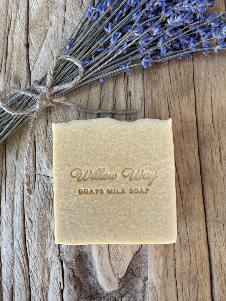 A bar of goats milk soap on a wooden board with lavender